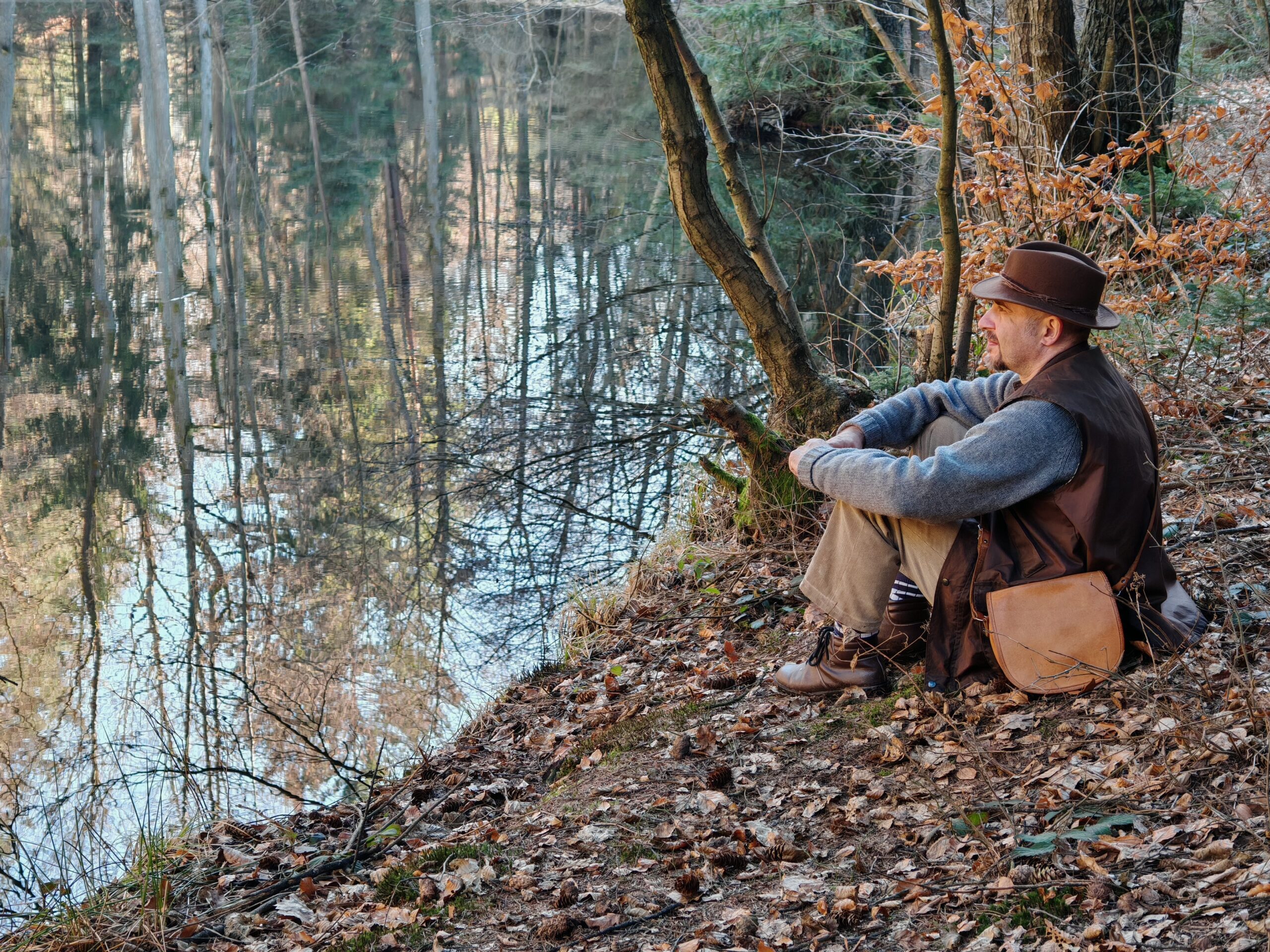 fotografie - malíř sedící na břehu jezera